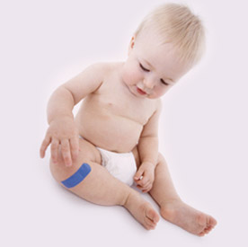 baby touching knee with band aid on it